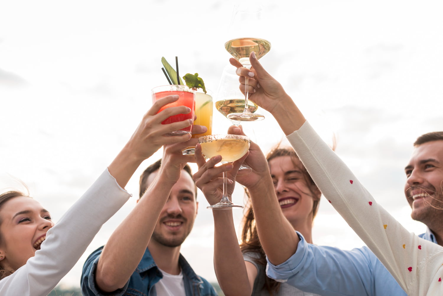 Friends raising cocktail glasses together in a toast